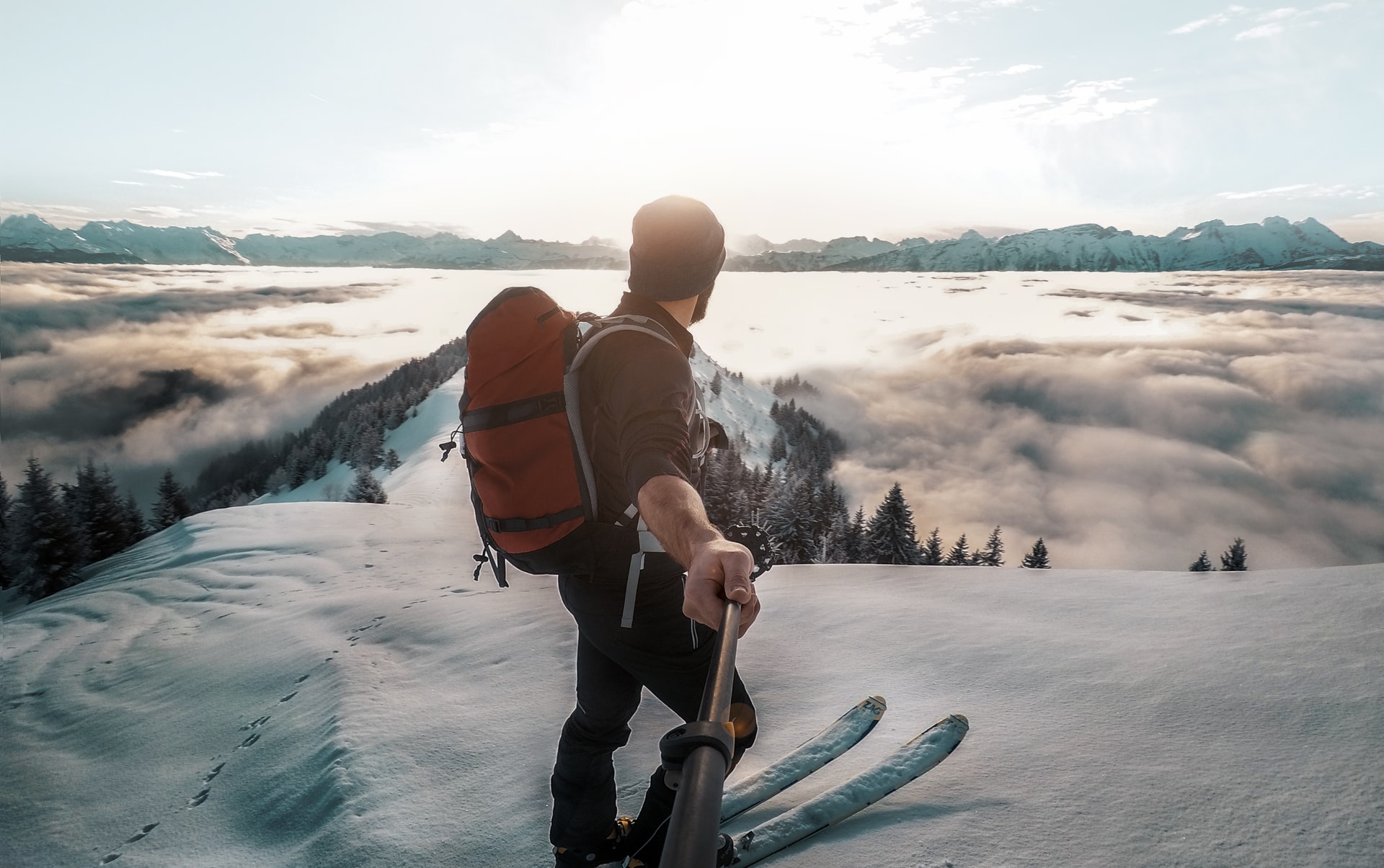 Mężczyzna na nartach w górach trzyma w ręce kamere którą nagrywa krajobraz